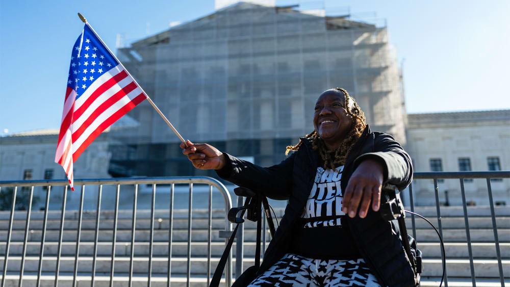 A Black demonstrator holds a US flag outside the US Supreme Court in D.C.