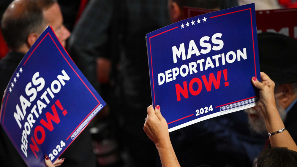 A person holds a sign that reads "Mass Deportation Now" during the third day of the Republican National Convention.