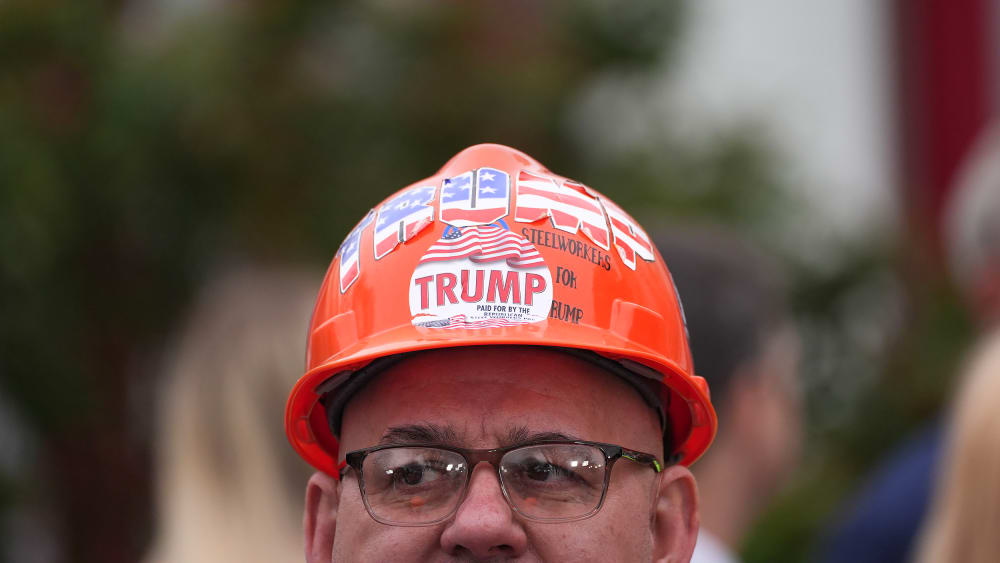 An attendee wearing a hard hat decorated with "Trump" stickers during an event in the Rose Garden at the White House.