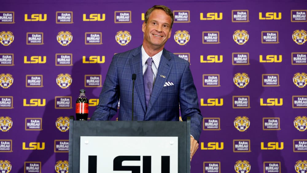 Lane Kiffin stands behind a podium at a press conference at Tiger Stadium in Baton Rouge, L.A.