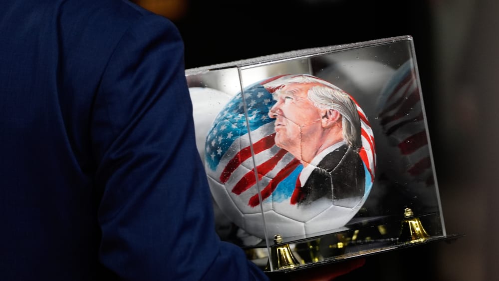 A person carries a soccer ball with a painting of President Donald Trump in D.C.