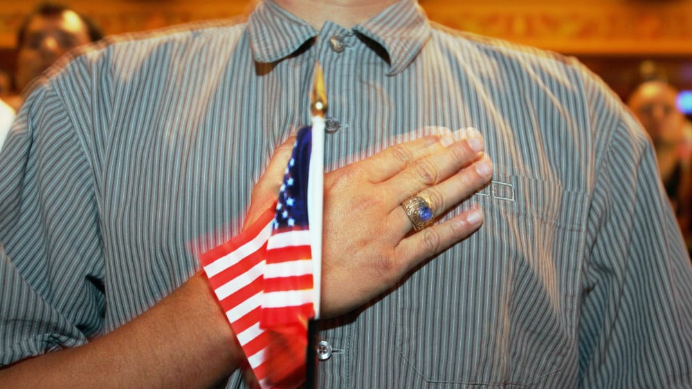 A person holds their hand up to their chest as they swear allegiance to the U.S. flag during a naturalization ceremony in Miami, F.L., on April 28, 2006.