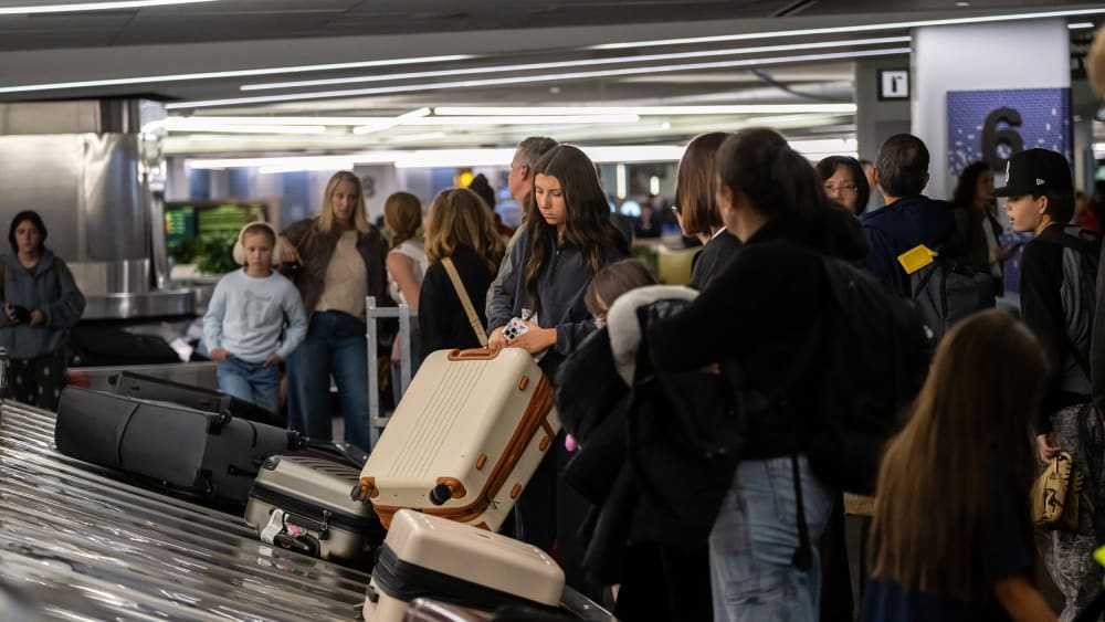 Travelers pick up luggage at a baggage carousel at San Francisco International Airport.
