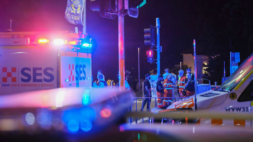 Emergency responders at Sydney's Bondi Beach in Australia confer amid the flashing lights of EMS vehicles.
