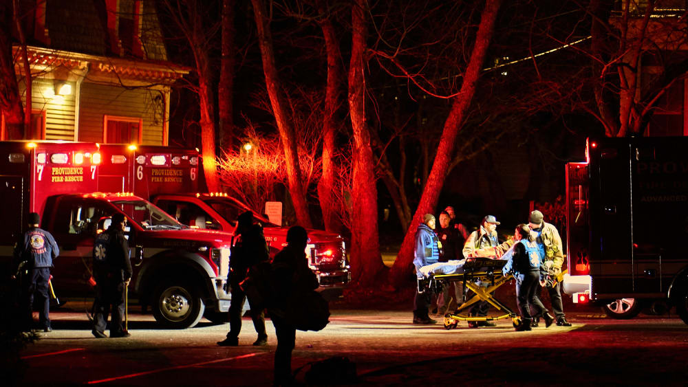 First responders wheel an empty gurney into an ambulance on Brown University campus.