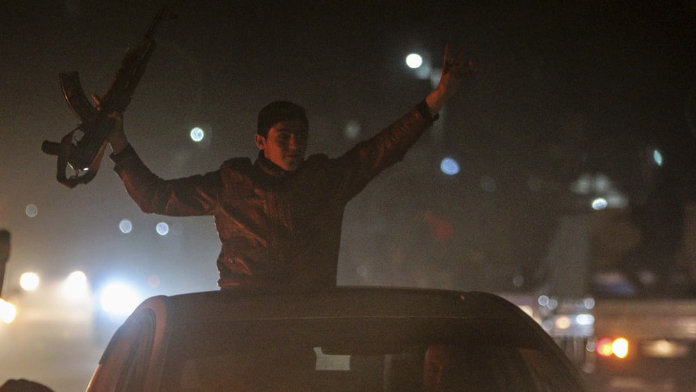 A Kurdish man holds up a weapon as he tours with others the streets of Ras al-Ain in celebration, after it was reported that Kurdish forces took control of the Syrian town of Kobani, Jani 26, 2015.