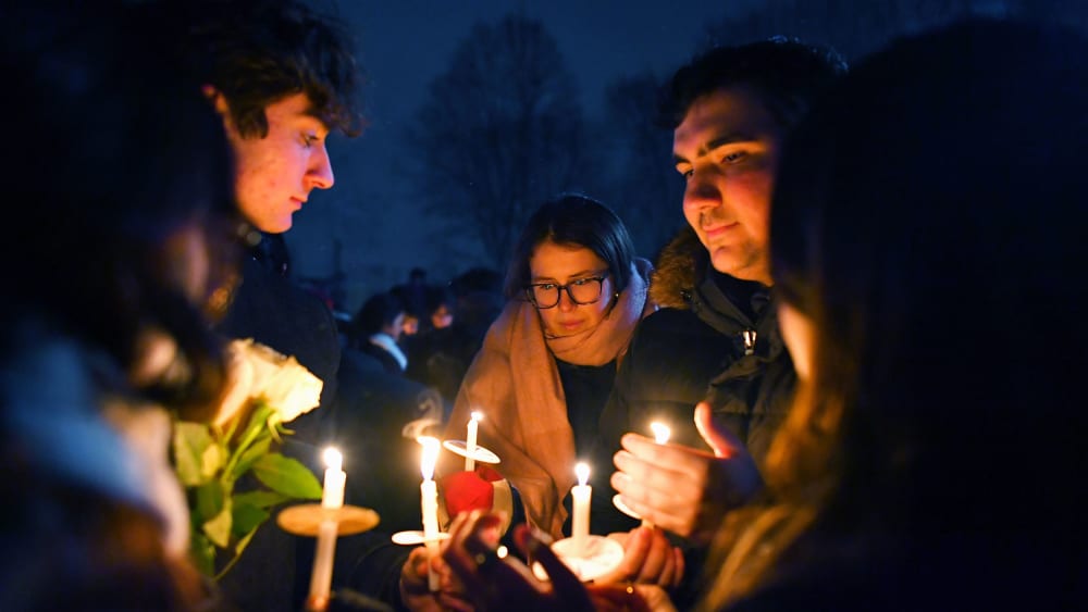 People hold candles during a vigil for those injured and killed during the Saturday shooting at Brown University.