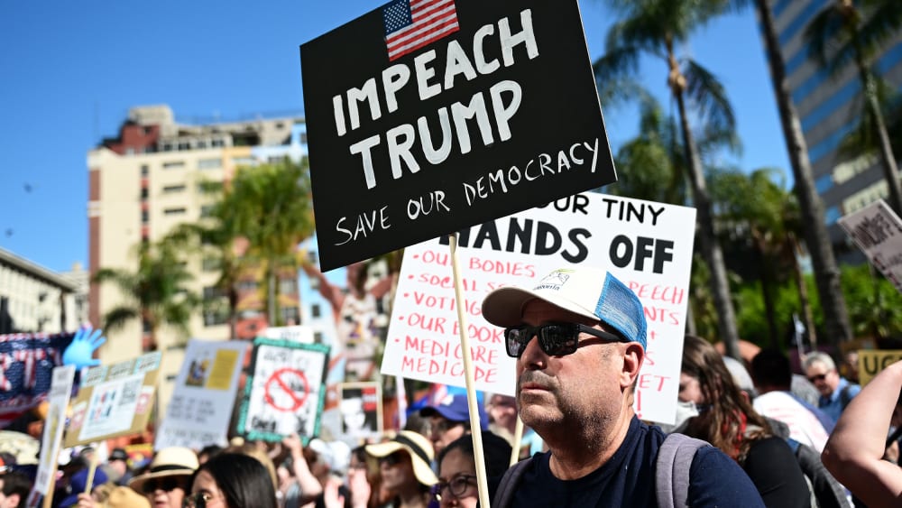A protester holds a sign reading "Impeach Trump" during a "Hands Off!" rally in on April 05, 2025 in Los Angeles.