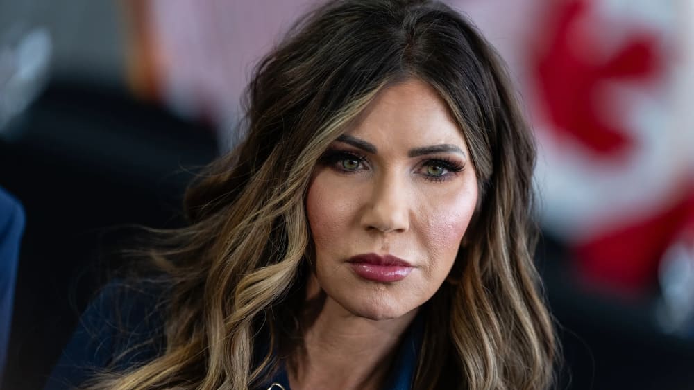 A tight tilted photo of Kristi Noem shows her displeased.