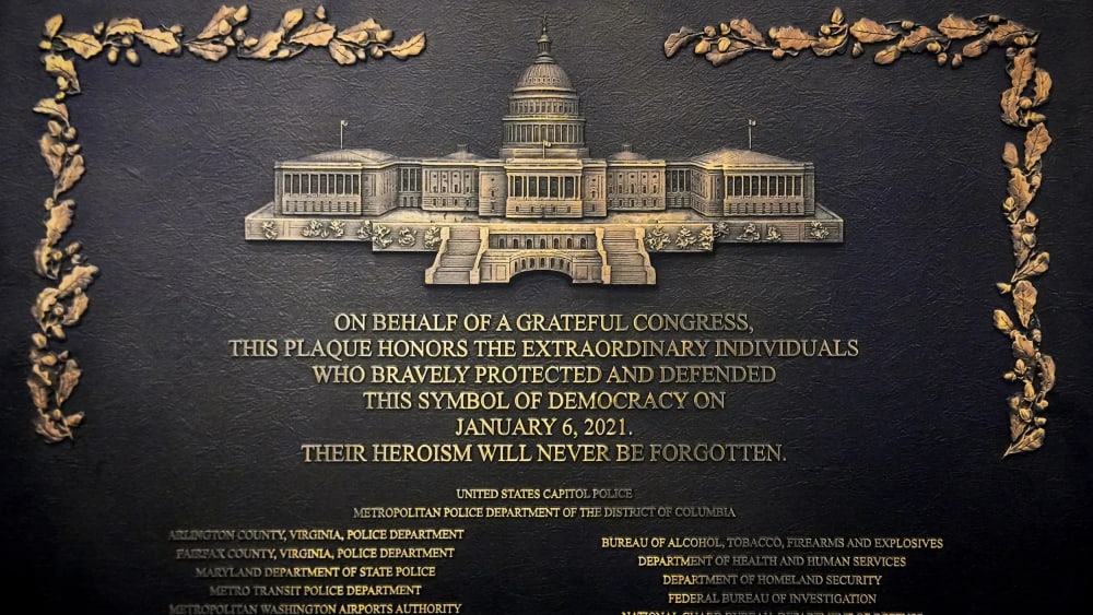 A plaque reads, "On behalf of a grateful Congress, this plaque honors the extraordinary individuals who bravely protected and defended this symbol of democracy on January 6, 2021. Their heroism will never be forgotten."