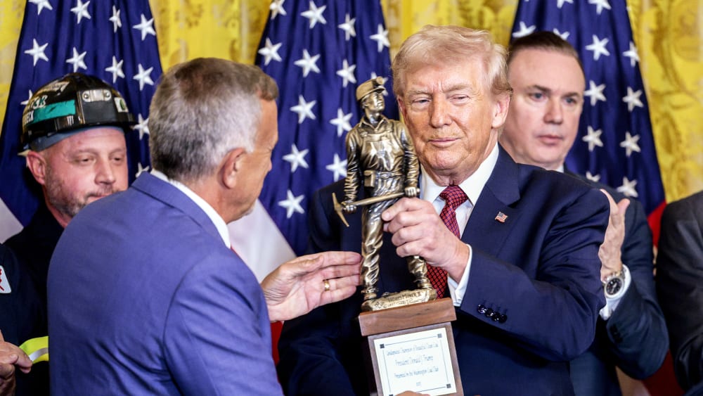 Jim Grech, president and chief executive officer of Peabody Energy Corp., presents President Donald Trump with a trophy during a "Champion of Coal" event in the East Room of the White House.