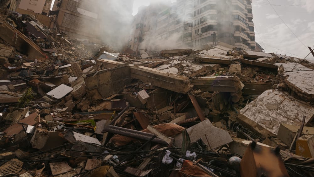 A man stands atop the rubble of a building destroyed in an Israeli airstrike near Beirut