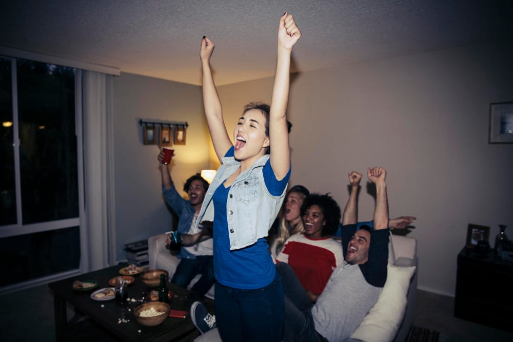 Friends cheering while watching sports on TV at home