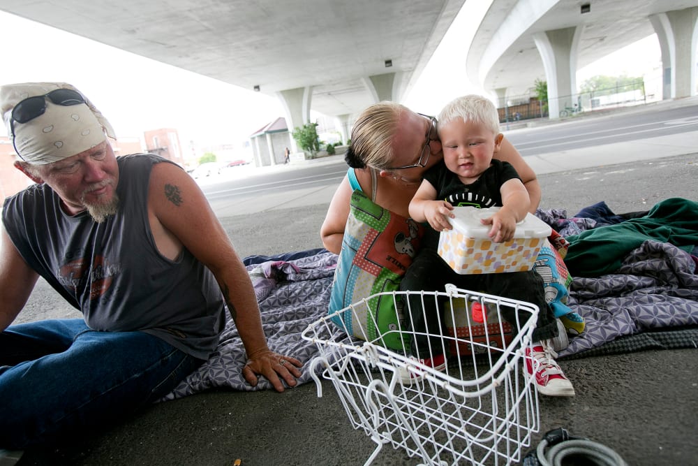 Tealla Dilka, with her husband Will at left, plays with her 18-month-old son David as they lay on the asphalt underneath the 16th Street bridge in Boise, Idaho on June 25, 2014.