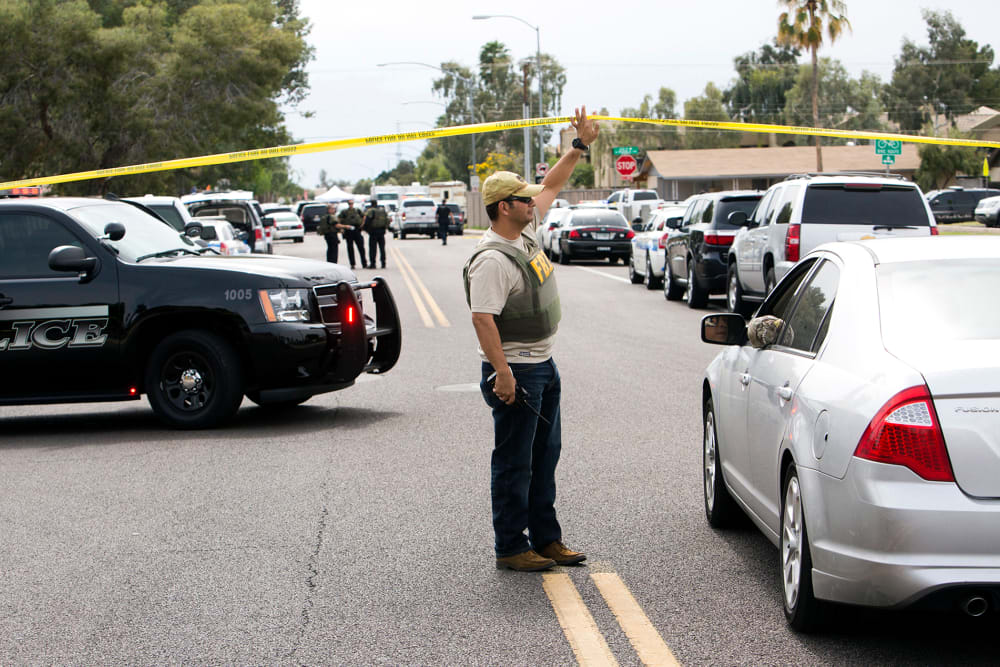 An FBI agent lifts police tape at one of the scenes of a multiple location shooting that has injured at least four people in Mesa, Arizona on March 18, 2015. (Photo by Deanna Dent/Reuters)