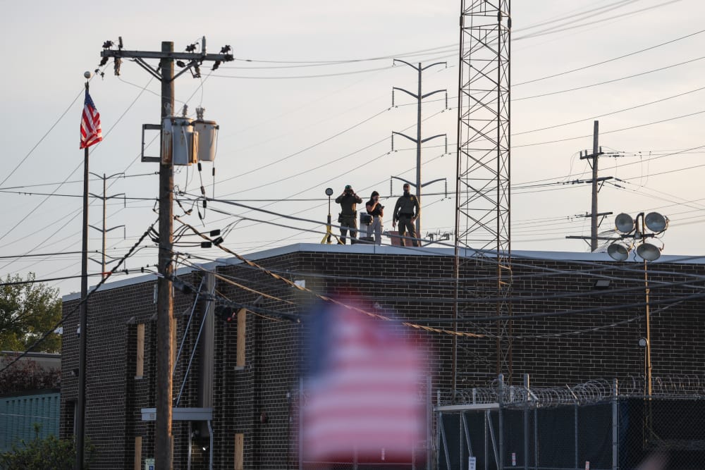 People on the roof of the immigration processing and detention center watch demonstrators in Broadview, I.L.