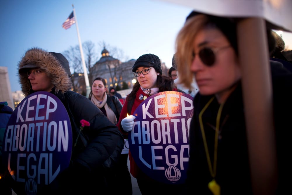 Attendees listen during a candlelight vigil organized by the National Organization for Women in front of the U.S. Supreme Court, Jan. 22, 2013.