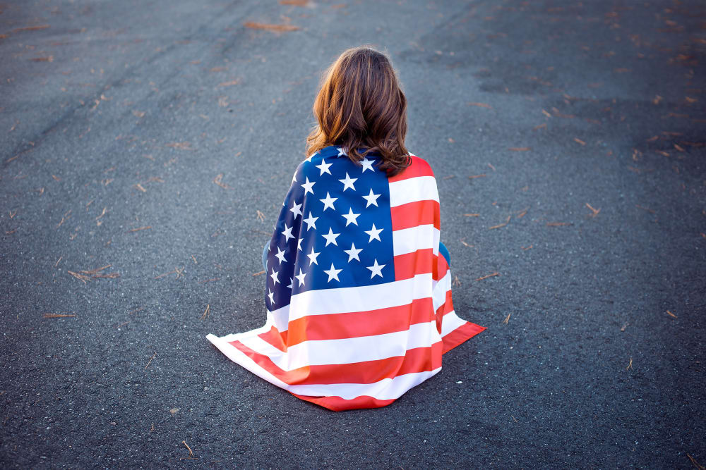 Sad lonely patriot woman sitting down with the american flag
