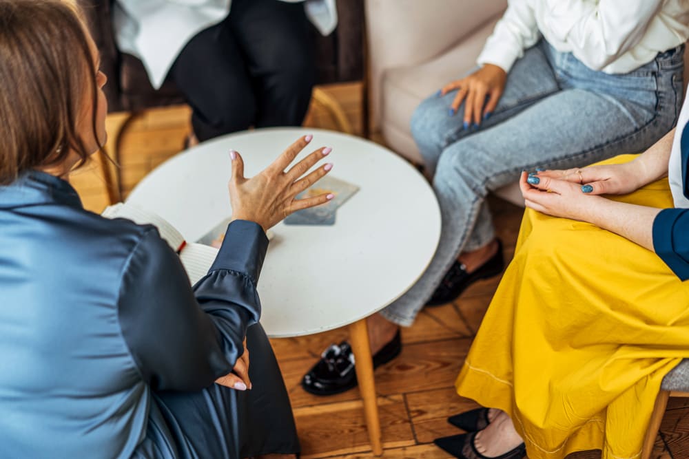 Four women in armchairs and talking.