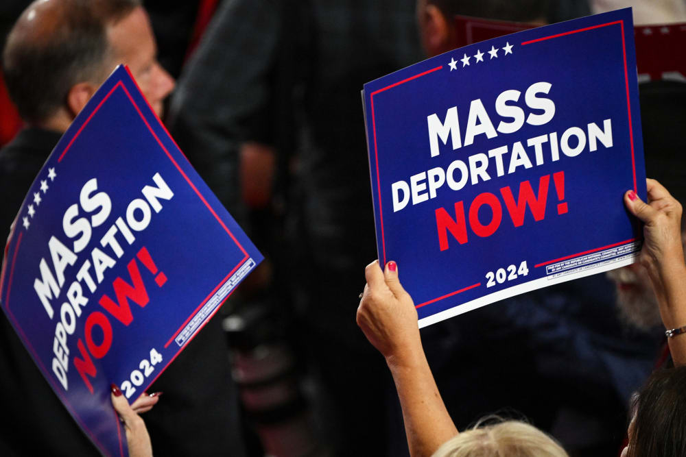 A person holds a sign that reads "Mass Deportation Now" during the third day of the Republican National Convention.
