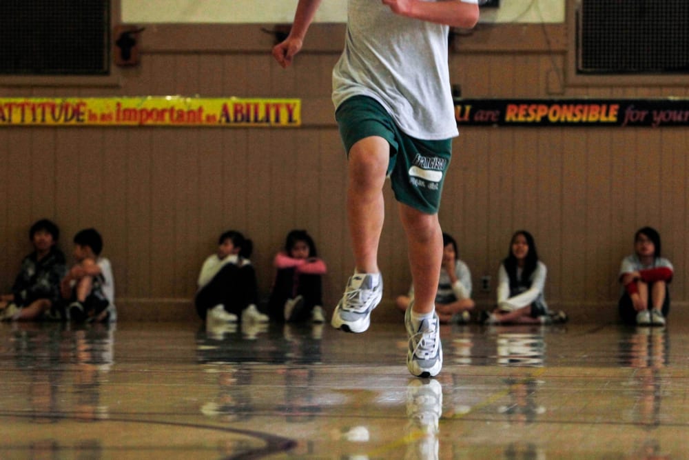 A student runs across the gym floor