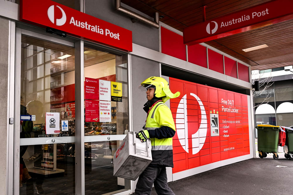 Image: A postman enters an Australia Post store