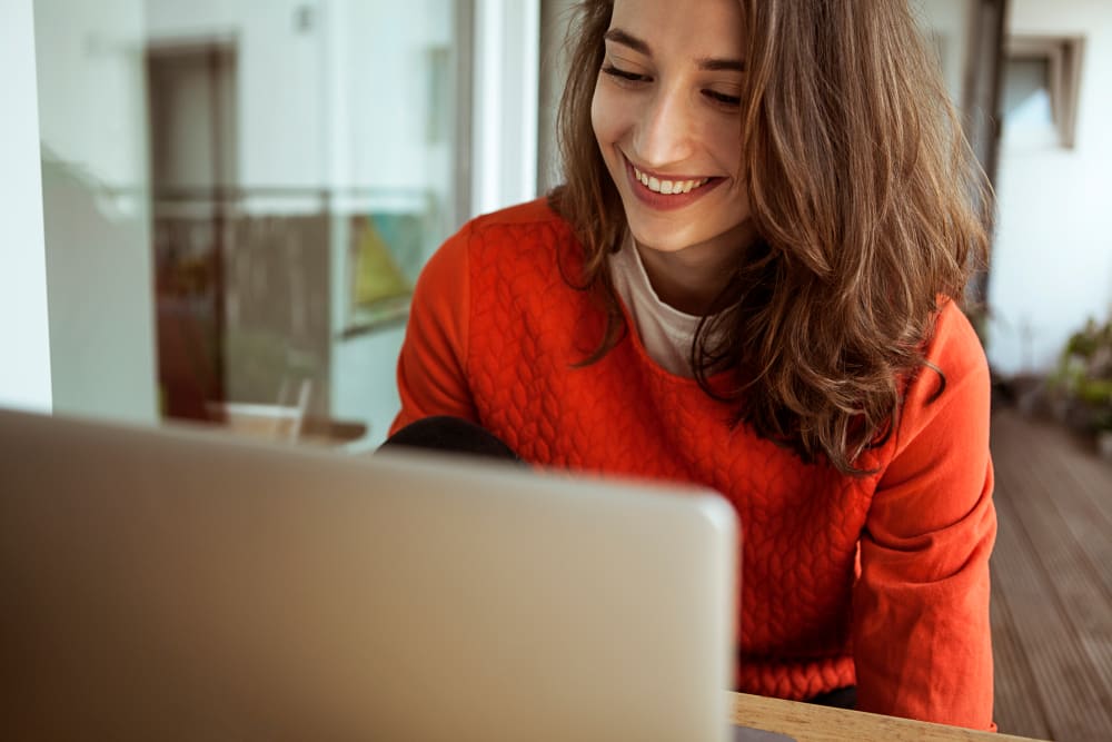 Smiling young woman using laptop on balcony