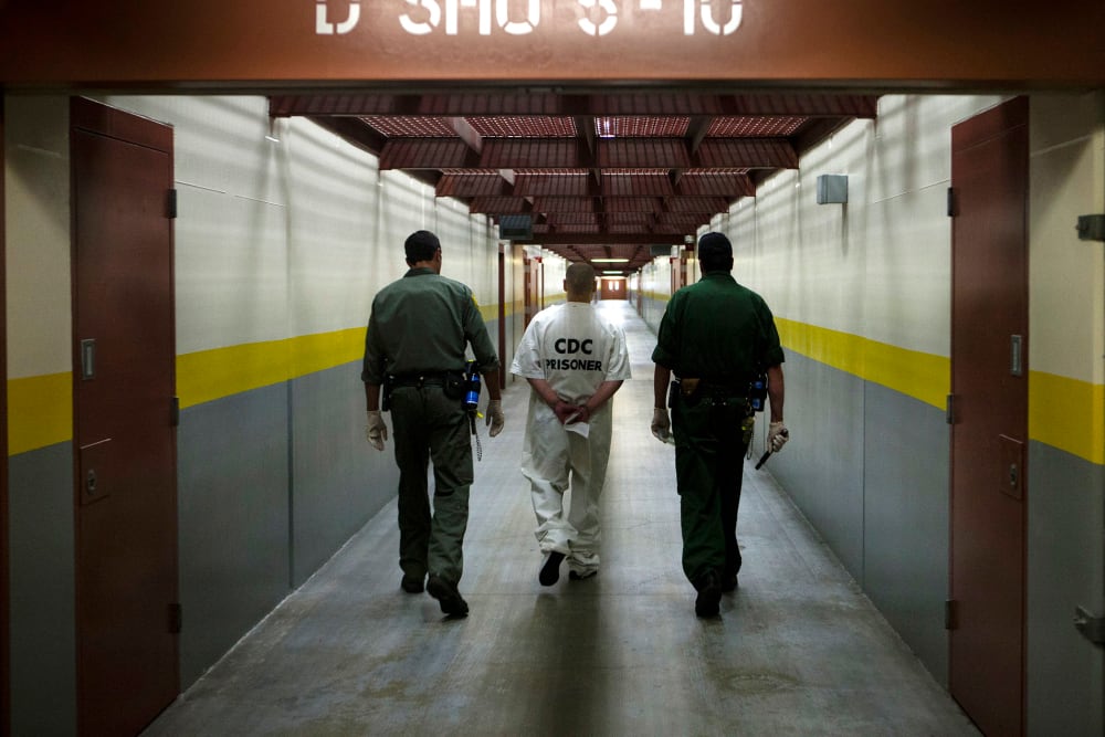 Two correction officers escort a prisoner down a corridor at Pelican Bay Prison in Crescent City, Calif. on June 8, 2012.