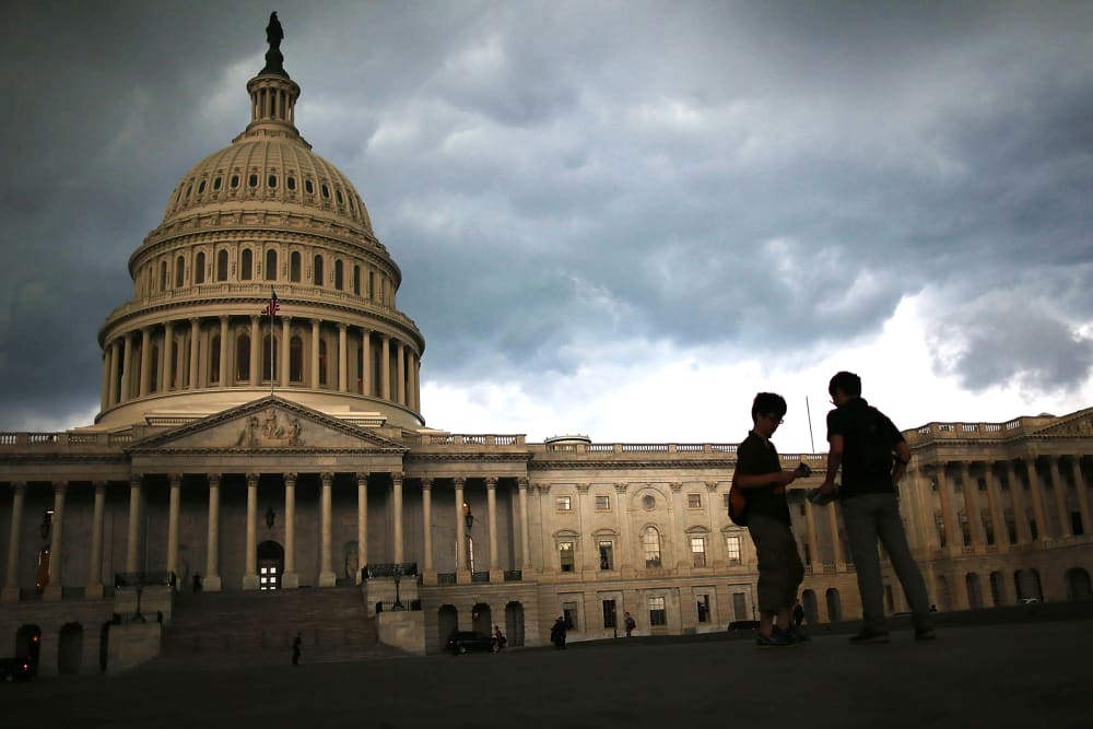 Two men stand on the plaza of the U.S. Capitol Building as storm clouds fill the sky, June 13, 2013 in Washington, DC.