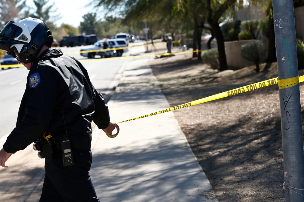A Phoenix Police Department officer puts up police tape near a crime scene on Jan. 30, 2013. (Photo by Ross Franklin/AP)