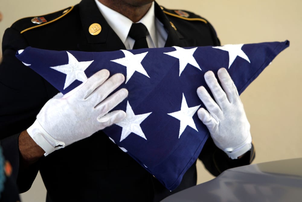 An Army National Guardsman, holds an American flag during a funeral.