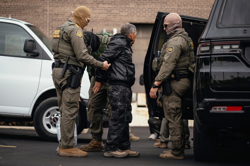 Immigration and Customs Enforcement agents take people they detained earlier to a parking lot before transferring them to an ICE facility in Chicago.