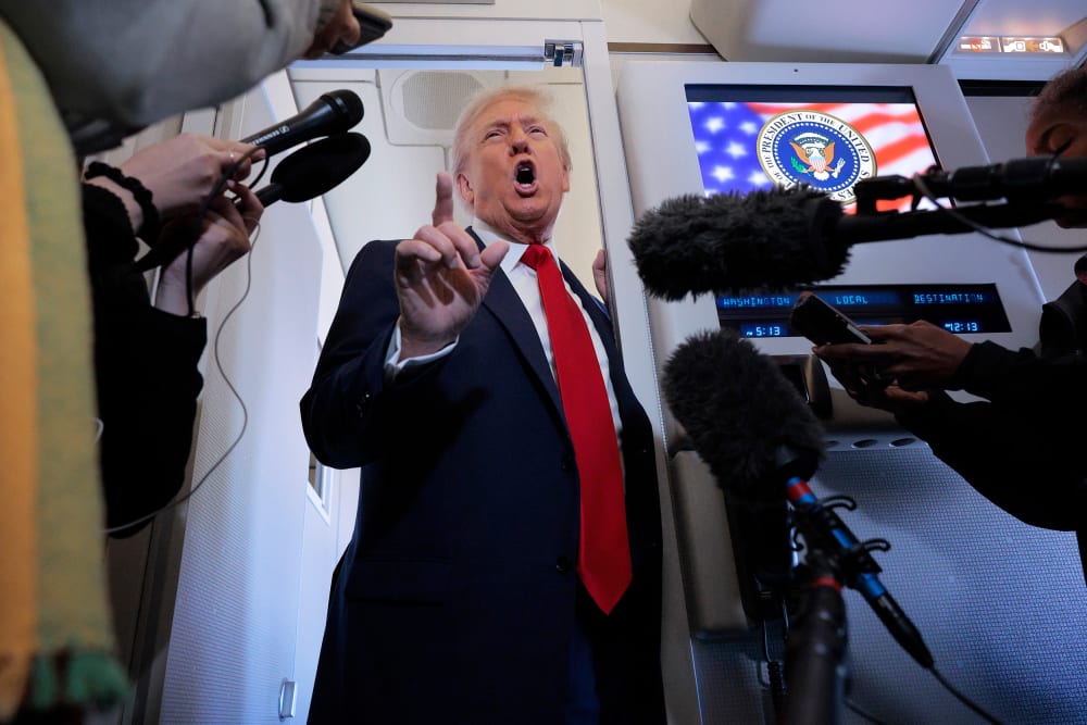 President Donald Trump talks to reporters on board Air Force One.