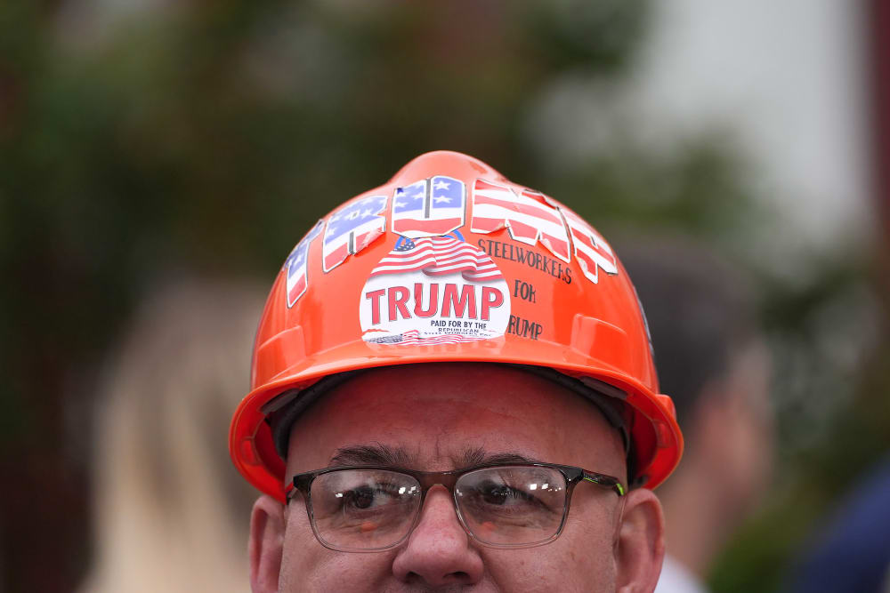 An attendee wearing a hard hat decorated with "Trump" stickers during an event in the Rose Garden at the White House.
