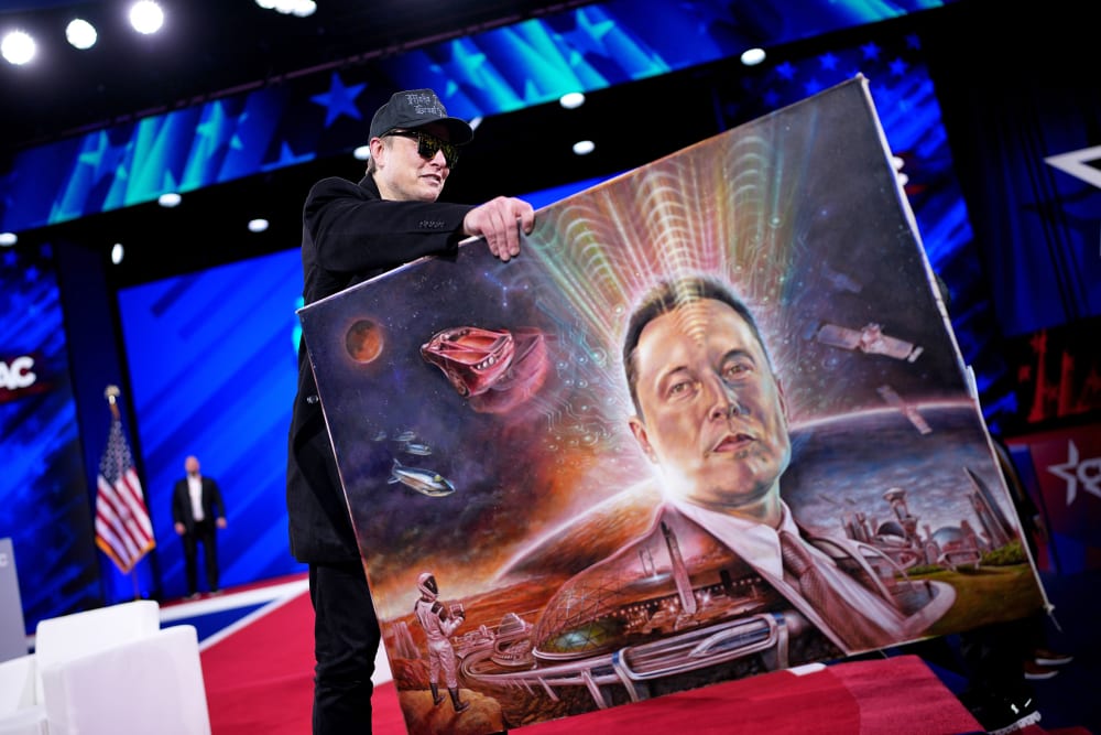 Elon Musk holds a painting of himself.