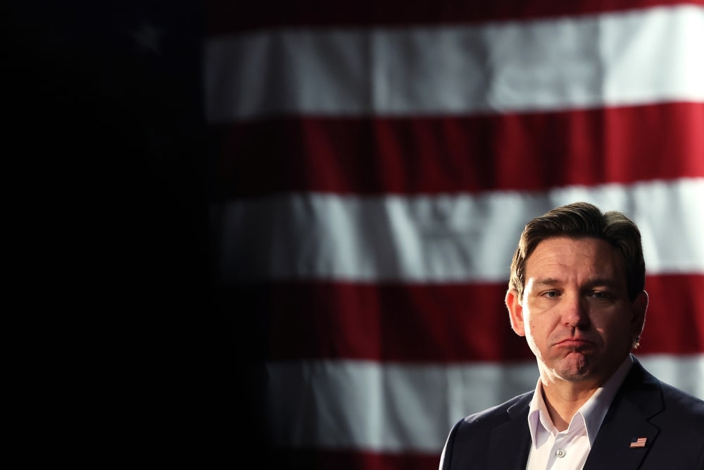 Florida Gov. Ron DeSantis frowning in front of an American flag.