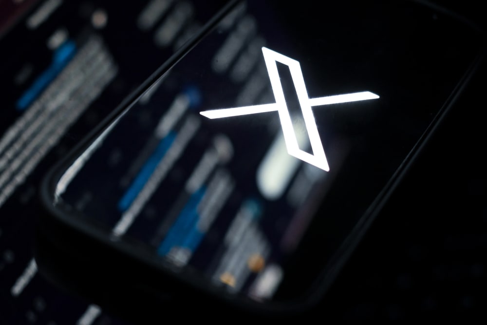The web version of X mirrored onto a phone showing the X logo.