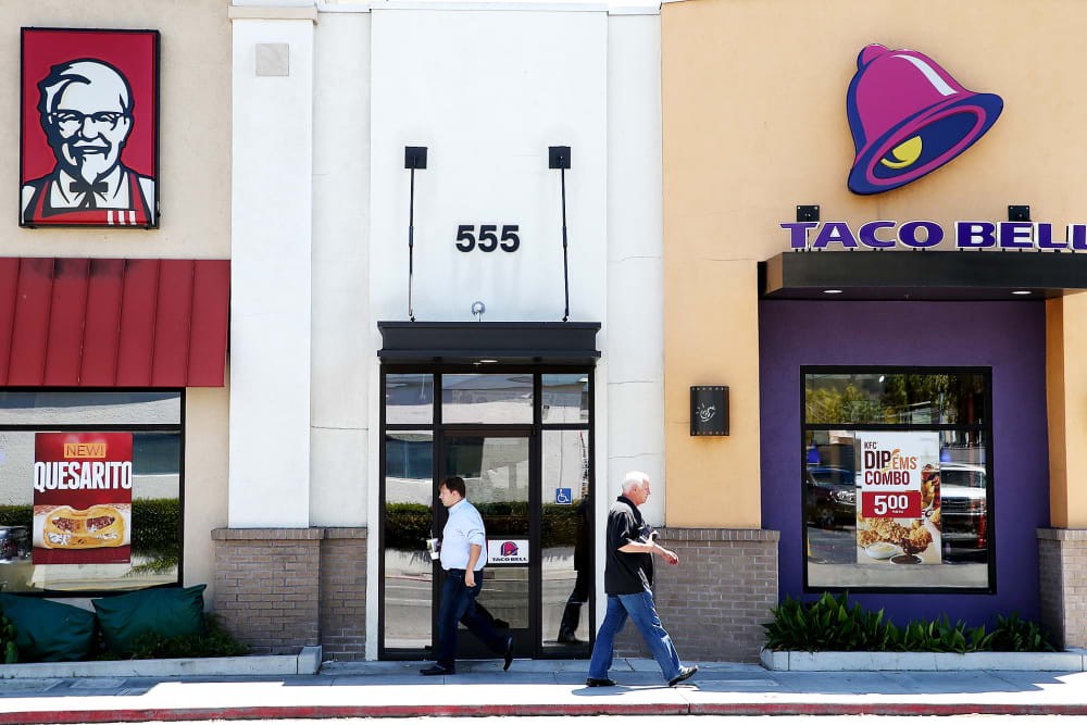 Pedestrians walk by a KFC and a Taco Bell restaurant on July 2, 2014 in San Rafael, California.