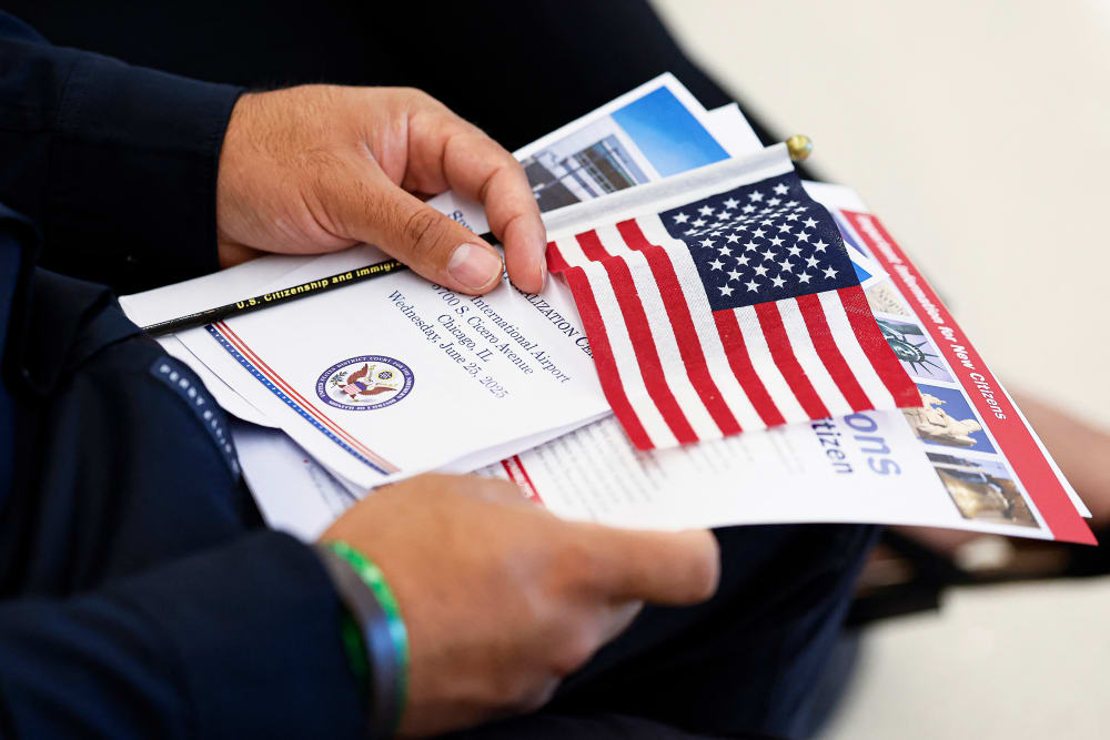 A new US citizen holds a program waiting to take the Oath of Allegiance before receiving their naturalization certificates.