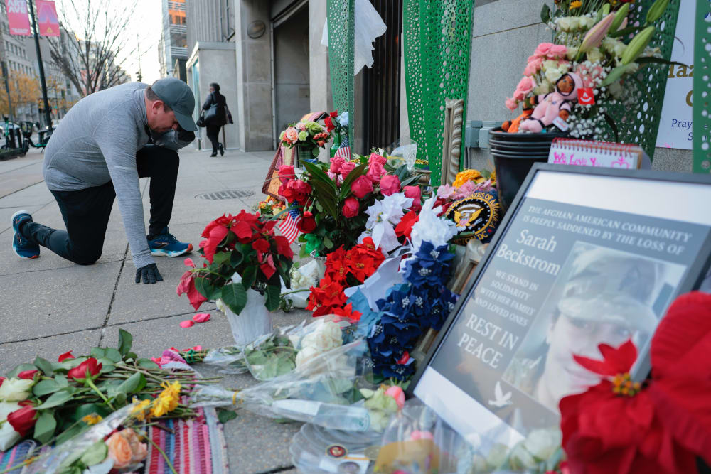 A jogger stops to pray at a makeshift memorial of flowers and American flags outside the Farragut West Metro station on Dec. 1, 2025, in Washington, D.C.