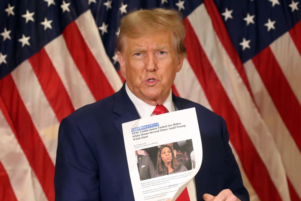 Then former U.S. President Donald Trump holds up a news story about New York Attorney General Letitia James as he speaks to the media at one of his properties at 40 Wall Street following closing arguments at his civil fraud trial on Jan. 11, 2024, in New York City.