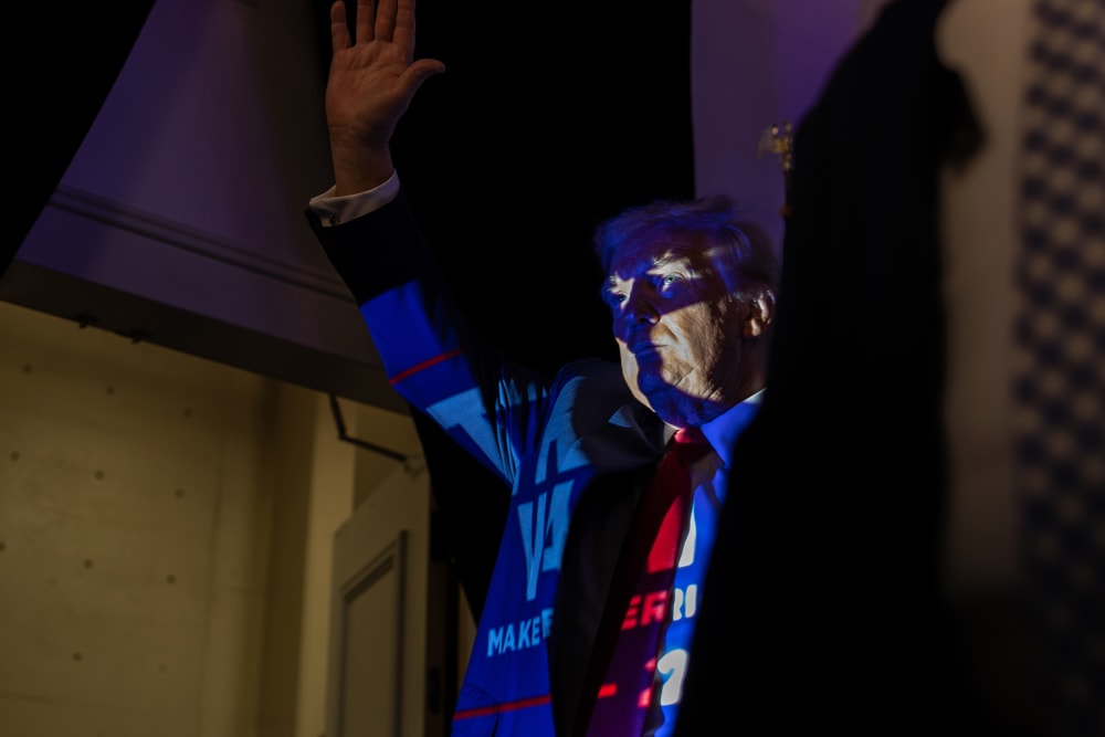 Donald Trump in Charlotte, N.C., with a projection of a Trump 2024 poster casting onto him.