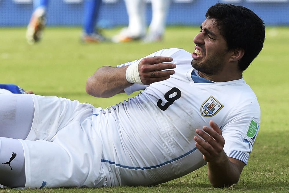Uruguay forward Luis Suarez puts his hand to his mouth after clashing with Italy's defender Giorgio Chiellini, June 24, 2014.