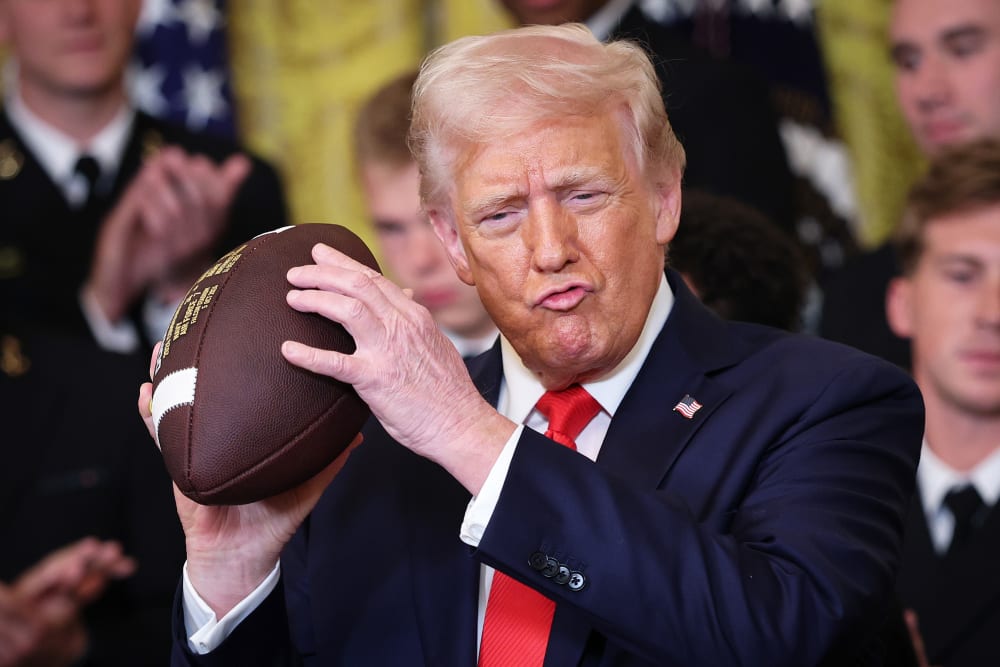 President Donald Trump holds up a football presented to him during a presentation ceremony for the Commander-in-Chief Trophy in the White House on April 15, 2025.