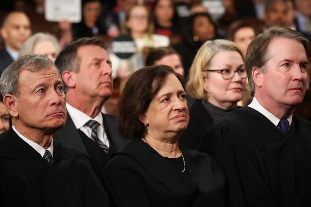 Justice Elena Kagan sits between Chief Justice of the Supreme Court John Roberts and Justice Brett Kavanaugh.
