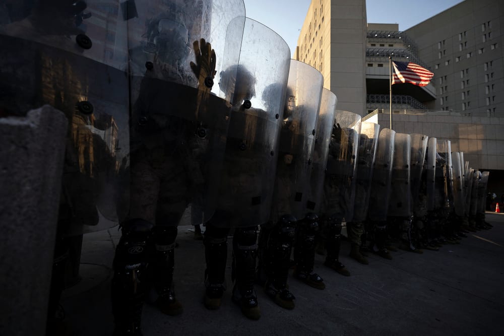 National guards stand in front of the entrance of the Metropolitan Detention Center as demonstrators gather in front of it following federal immigration operations in Los Angeles, CA.