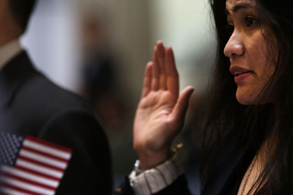 People hold up their right hands during a naturalization ceremony at Federal Hall for approximately 75 citizenship candidates from 31 countries on May 22, 2014 in New York City.