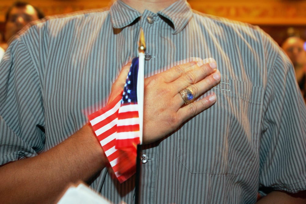 A person holds their hand up to their chest as they swear allegiance to the U.S. flag during a naturalization ceremony in Miami, F.L., on April 28, 2006.