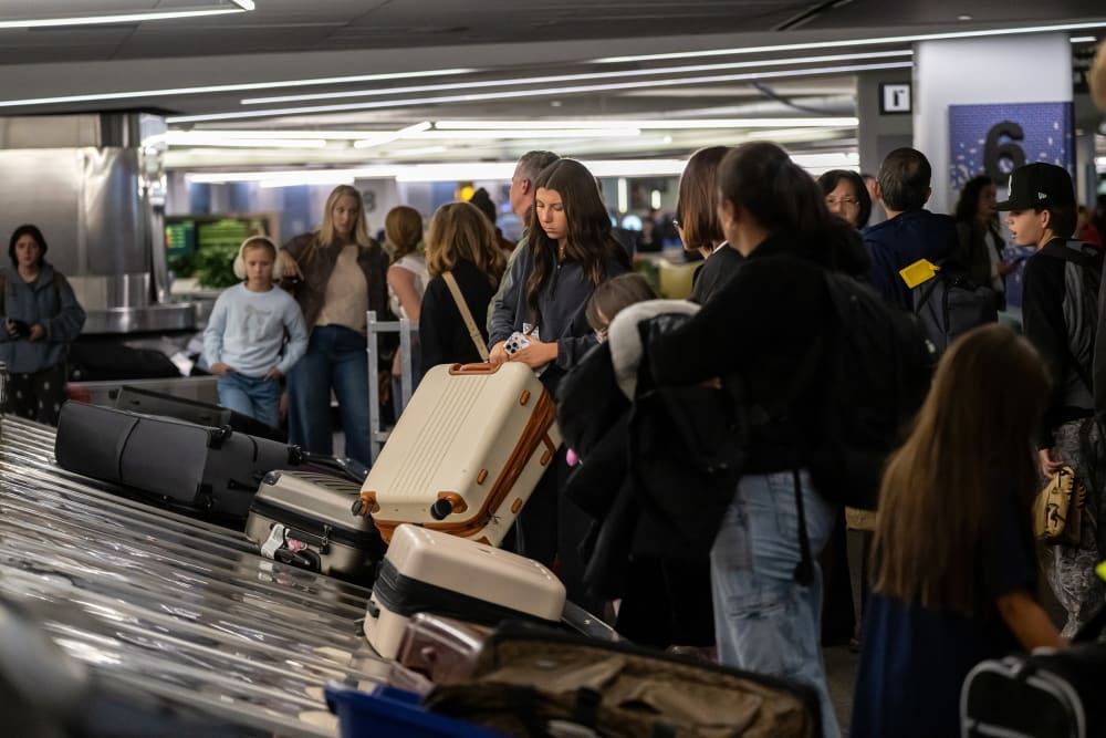 Travelers pick up luggage at a baggage carousel at San Francisco International Airport.