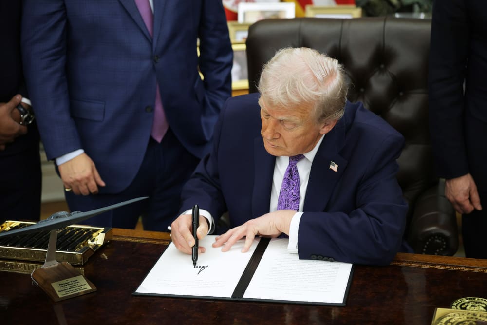 President Donald Trump signs an executive order in the Oval Office.
